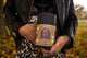 Cramp Comfort herbal tea canister labeled Cramp Relief, held by a person in a leather jacket over leopard print